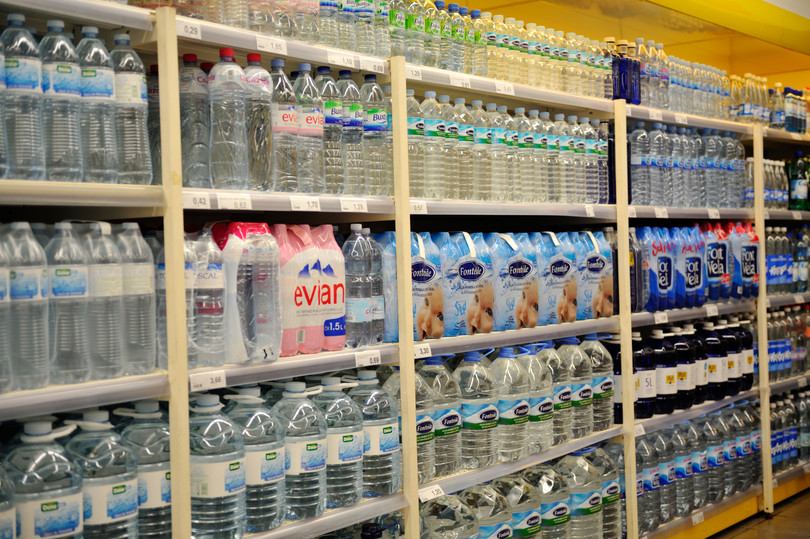 Estantes llenos de agua embotellada a la venta en un supermercado: Charles Stirling (Travel)